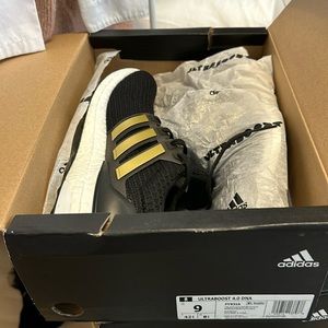New men’s Ultraboost 4.0 DNA running sneakers in black and gold